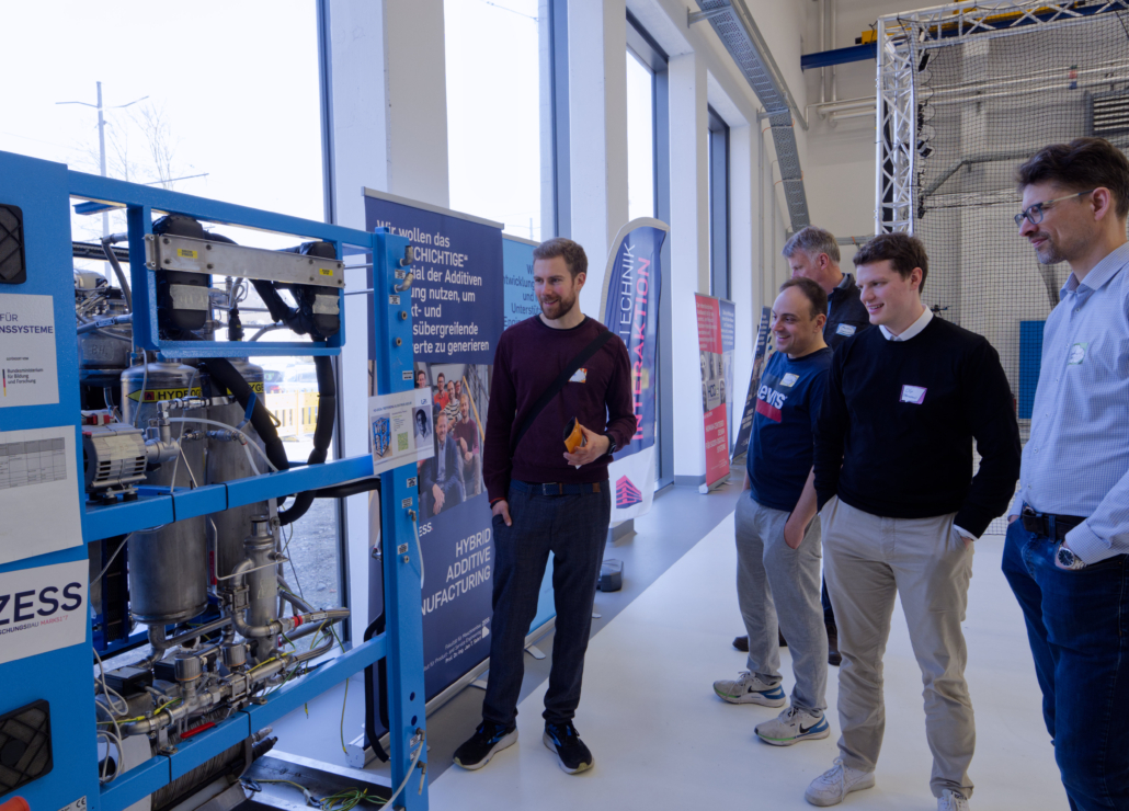 Mitglieder der CircuPEM-Projektgruppe betrachten einen Elektrolyseur am ZESS